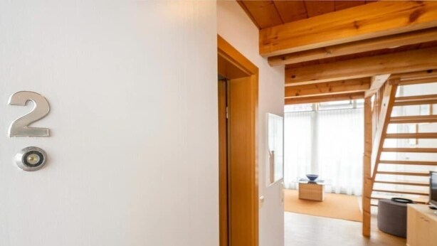 A modern interior with a wooden ceiling, a staircase, and a television on a wooden cabinet. - Holiday apartment with 1 bedroom (Lindau (Bodensee))