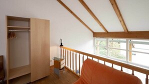 A room with a wooden ceiling, a window with a view, a glass table, and a chair. - Holiday apartment with 1 bedroom (Lindau (Bodensee))