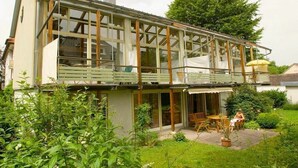 A modern house with a large glass balcony, a covered patio, and a garden area. - Holiday apartment with 1 bedroom (Lindau (Bodensee))