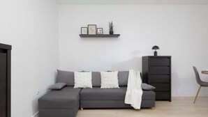 A modern living room with a grey sectional sofa, a small black cabinet, and a white throw blanket.