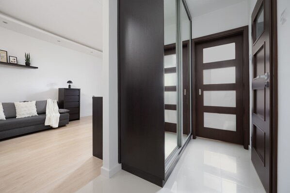 A modern living room with a dark-colored sofa, a small black cabinet, and a glass door leading to another room.