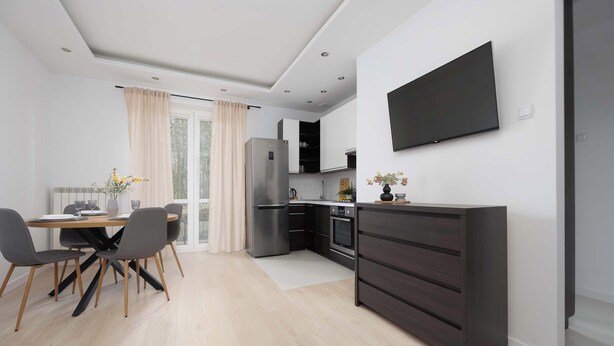 A modern kitchen with a built-in oven, a refrigerator, and a flat-screen TV mounted on the wall.