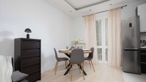 A modern kitchen with a built-in refrigerator, a dining table with chairs, and a large window with curtains.