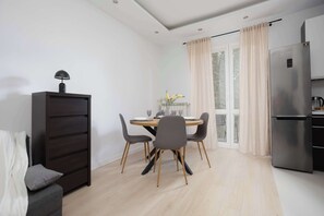Una cocina moderna con refrigerador empotrado, una mesa de comedor con sillas y un amplio ventanal con cortinas.