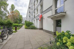 Un edificio residencial con una bandera, bicicletas y zonas verdes.