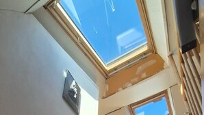 Escada de madeira que leva a um quarto com claraboias e uma pequena janela.
