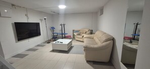 A living room with a flat-screen TV, a sofa, a coffee table, and a chair.