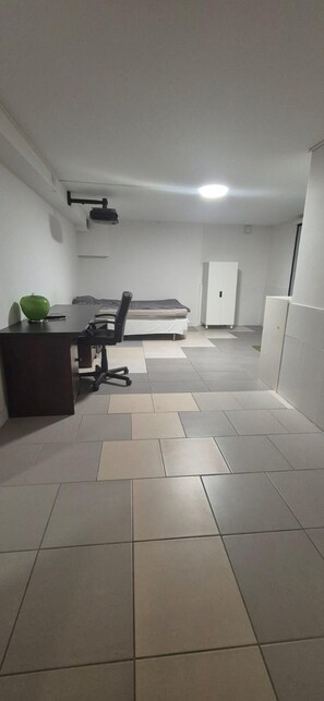 A room with a bed, a desk with a chair, a projector, and a wardrobe.