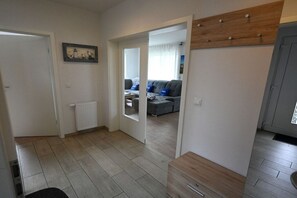 A hallway leading to a living area with a grey sofa and a wooden cabinet. - Holiday home in Burhave with swimming pool (Burhave)