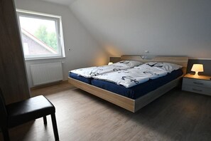 Een slaapkamer met een bed, nachtkastjes, een stoel, een raam en een radiator.