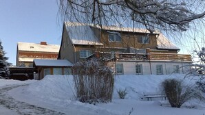 A two-story building with a sloped roof, surrounded by snow-covered ground and sparse vegetation. - Holidays at Bärbel Güldner's (Feldberger Seenlandschaft)