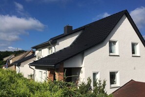 Ett tvåvåningshus med ett sluttande tak, en satellitparabol och en liten balkong.