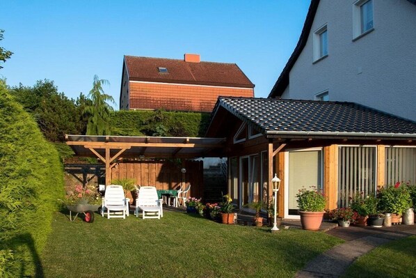 Een woonhuis met een overdekte patio, buitenmeubels en een tuin.