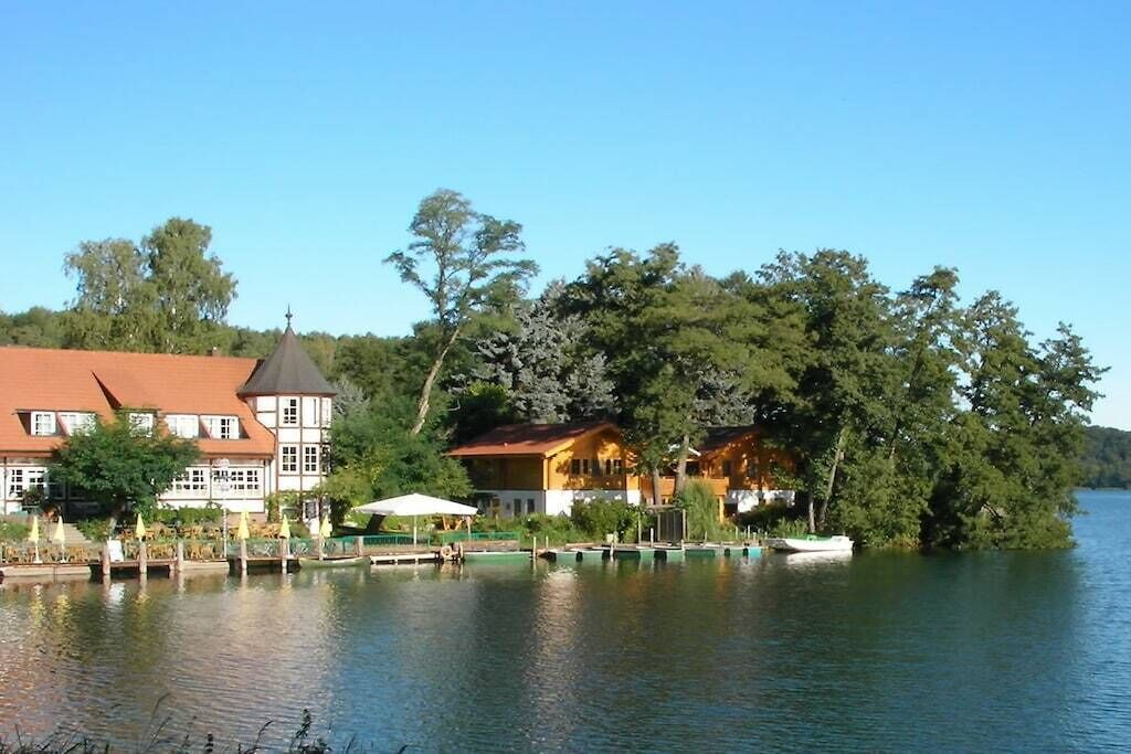 Une propriété située au bord d’un lac, dotée d’un quai, d’un bateau et de bâtiments au style architectural traditionnel.