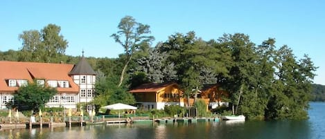 A lakeside property with a dock, a boat, and buildings with a traditional architectural style.
