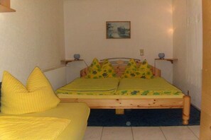 Een kamer met een bed, een slaapbank en een schilderij aan de muur.