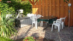 An outdoor patio with a stone floor, a barbecue grill, a table with chairs, and a wooden fence. - Holidays at Bärbel Güldner's (Feldberger Seenlandschaft)