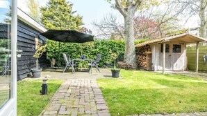 Un patio con mesa y sillas, un espacio de estar techado y un sendero de ladrillo.
