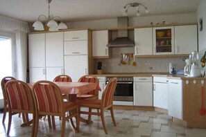 A compact kitchen with a dining table and chairs, a stove, oven, and white cabinets. - Holiday apartment with 1 bedroom (Meersburg)