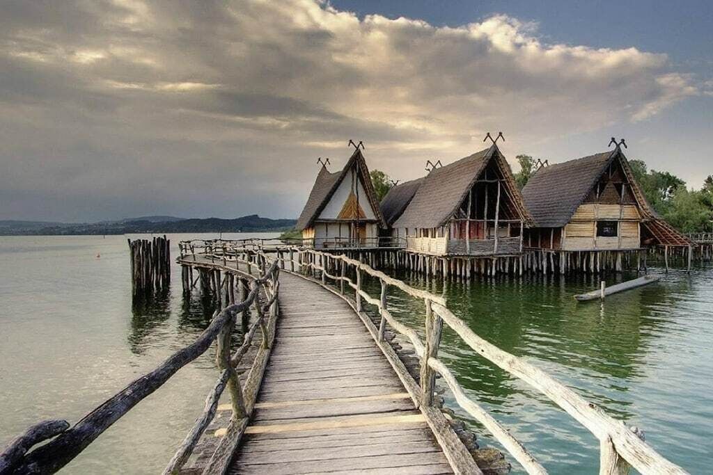 A wooden pier leading to traditional-style buildings over water.