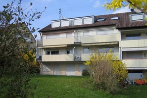 A multi-story residential building with balconies, a flat roof, and a small garden area. - Holiday apartment with 1 bedroom (Meersburg)