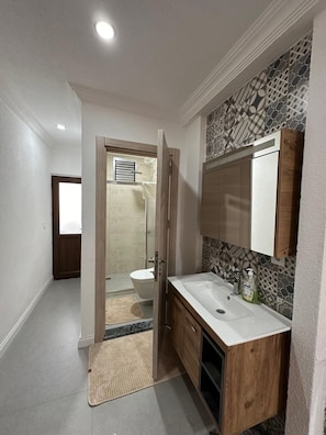 A modern bathroom with a wooden vanity, a large mirror, and a shower area. - Beach Room Suite İcmeler (Marmaris)