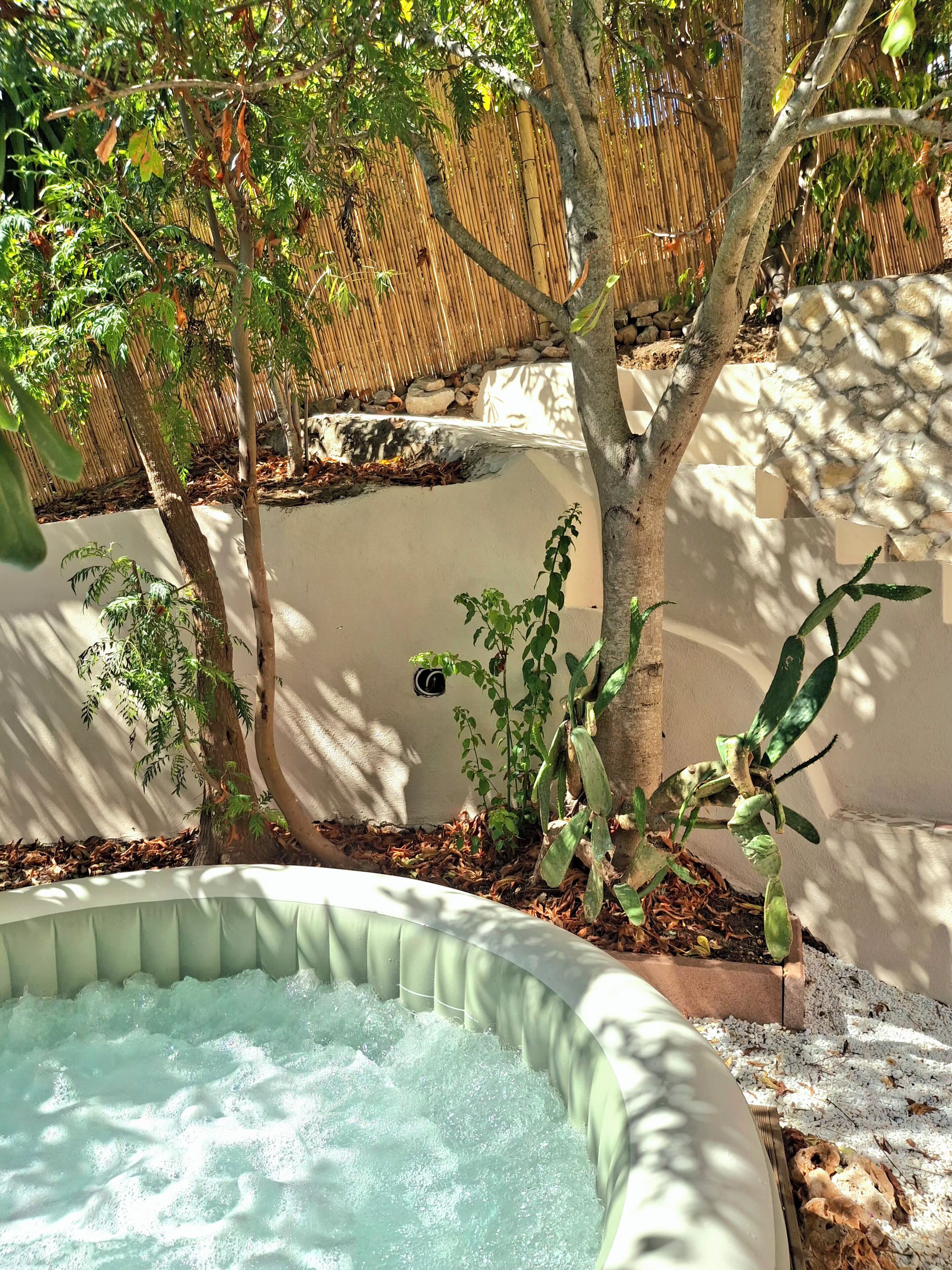 A hot tub surrounded by trees and a bamboo fence.