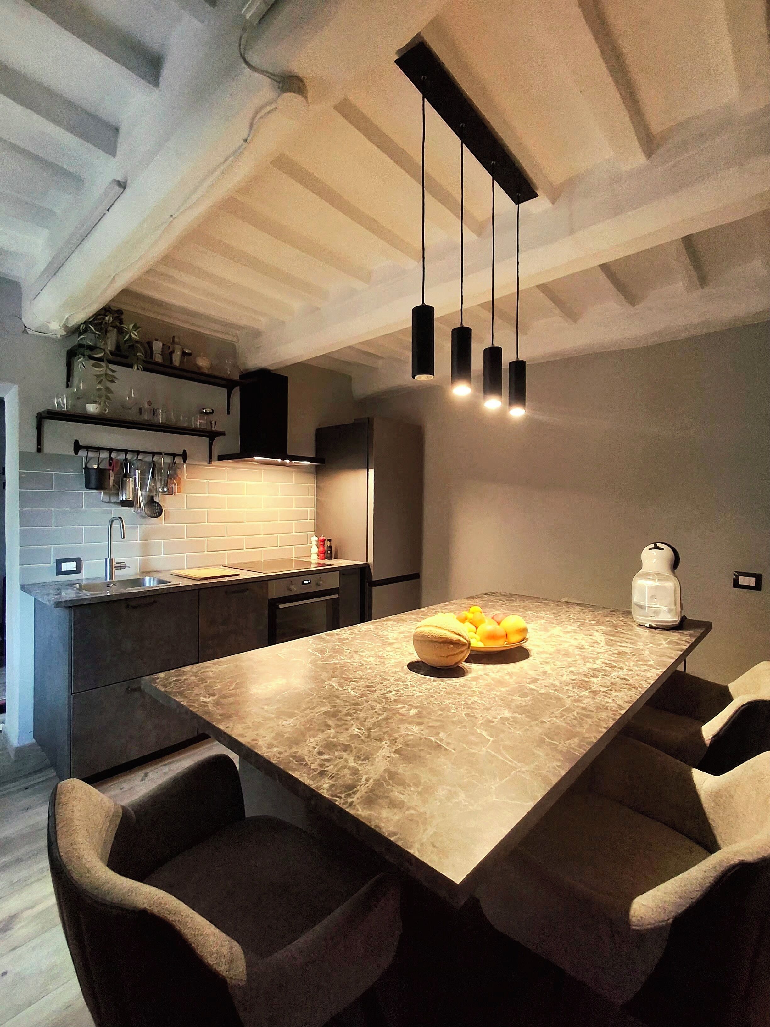 Une cuisine moderne dotée d’un plan de travail en marbre, de luminaires suspendus et d’un four encastré.