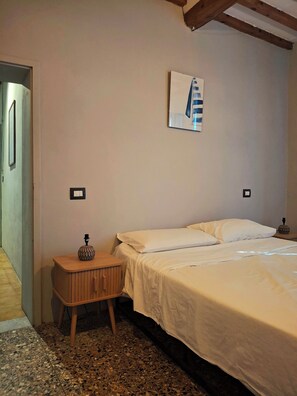 A bedroom with a bed, a nightstand, a wall-mounted artwork, and a door leading to another room. - Ganzo Tuscany Villa - Jacuzzi & Nature (Toscana)