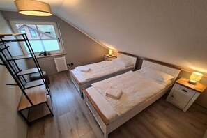 Ein Schlafzimmer mit zwei Betten, einer Holzleiter, einem Fenster und einer Heizung.