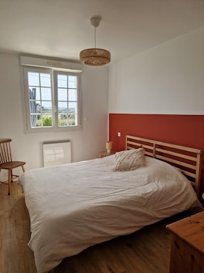 Une chambre à coucher avec un lit, une fenêtre, une chaise et une table de chevet.