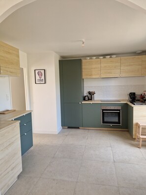 A kitchen with a built-in oven, wooden cabinets, and a tiled backsplash. - A house at the foot of the beaches and the GR34 trail, in the heart of the Côte des Légendes. (Kerlouan)