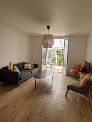 A modern living room with a sofa, a coffee table, and a chair. There is a sliding glass door leading to an outdoor area. - A house at the foot of the beaches and the GR34 trail, in the heart of the Côte des Légendes. (Kerlouan)