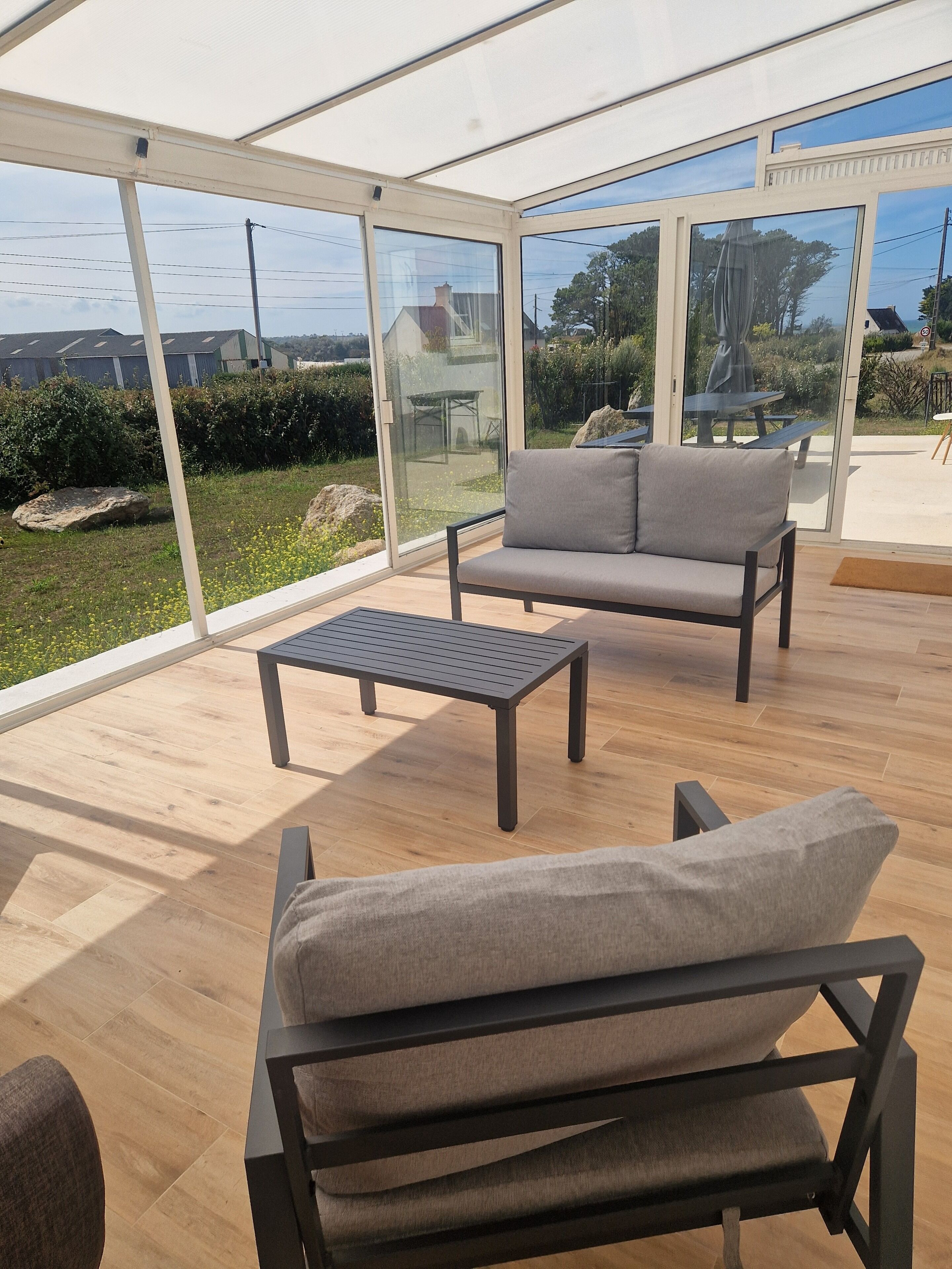 Ein Wintergarten mit einer Couch, einem Tisch und einem Sessel.