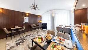 En modern hotellrestaurang med en frukostbuffé, olika typer av sittplatser och en bar.