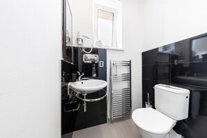 A modern bathroom with a white sink, a toilet, and a towel rack.