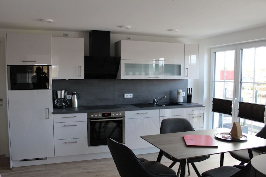 A modern kitchen with white cabinets, a microwave, and a dining area with a table and chairs.