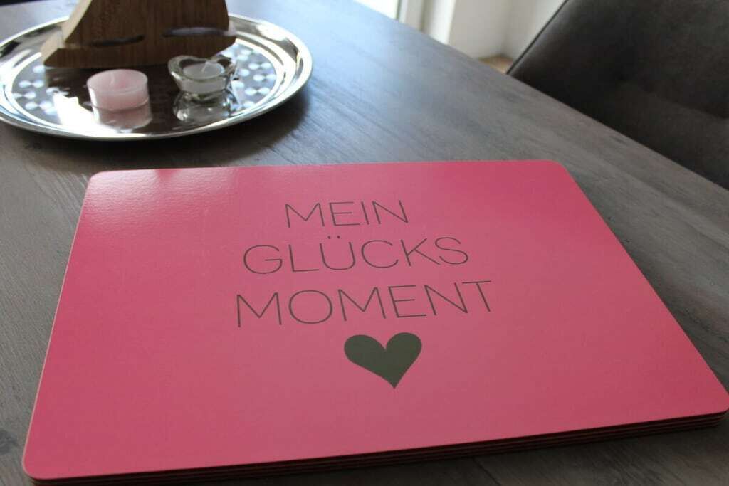 A pink notebook with the text 'MEIN GLÜCKS MOMENT' and a heart symbol on it.