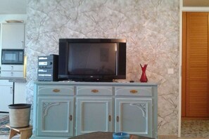 A television on a cabinet with drawers, a microwave above it, and a red vase on the cabinet. - Holiday apartment with 1 bedroom (Heiligenhafen)