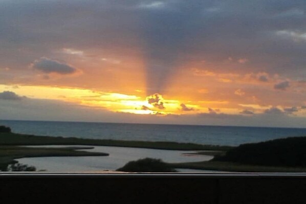 Een zonsondergang boven het wateroppervlak, met een weg op de voorgrond.