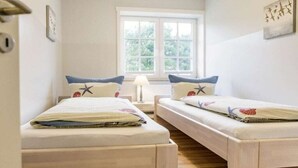 A room with two beds, a window, a lamp, and a door. - Holiday apartment in Nebel with swimming pool (Nebel)