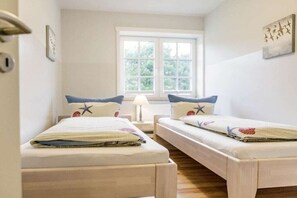 A room with two beds, a window, a lamp, and a door. - Holiday apartment in Nebel with swimming pool (Nebel)