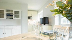 A modern kitchen with white cabinets, a microwave, and a television. - Holiday apartment in Nebel with swimming pool (Nebel)