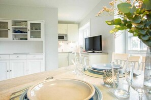 A modern kitchen with white cabinets, a microwave, and a television. - Holiday apartment in Nebel with swimming pool (Nebel)
