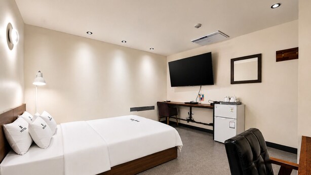 Une chambre d’hôtel équipée d’un lit, d’un bureau, d’une chaise, d’une télévision et d’un mini-bar.
