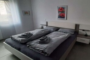 Een moderne slaapkamer met een bed, nachtkastjes en een schilderij aan de muur.