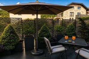 Eine Terrasse im Freien mit Tisch, Stühlen und Sonnenschirm.