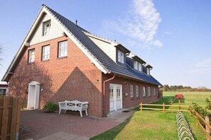 Ein zweistöckiges Backsteinhhaus mit geneigtem Dach, einer Haustür und einem kleinen Vordach.