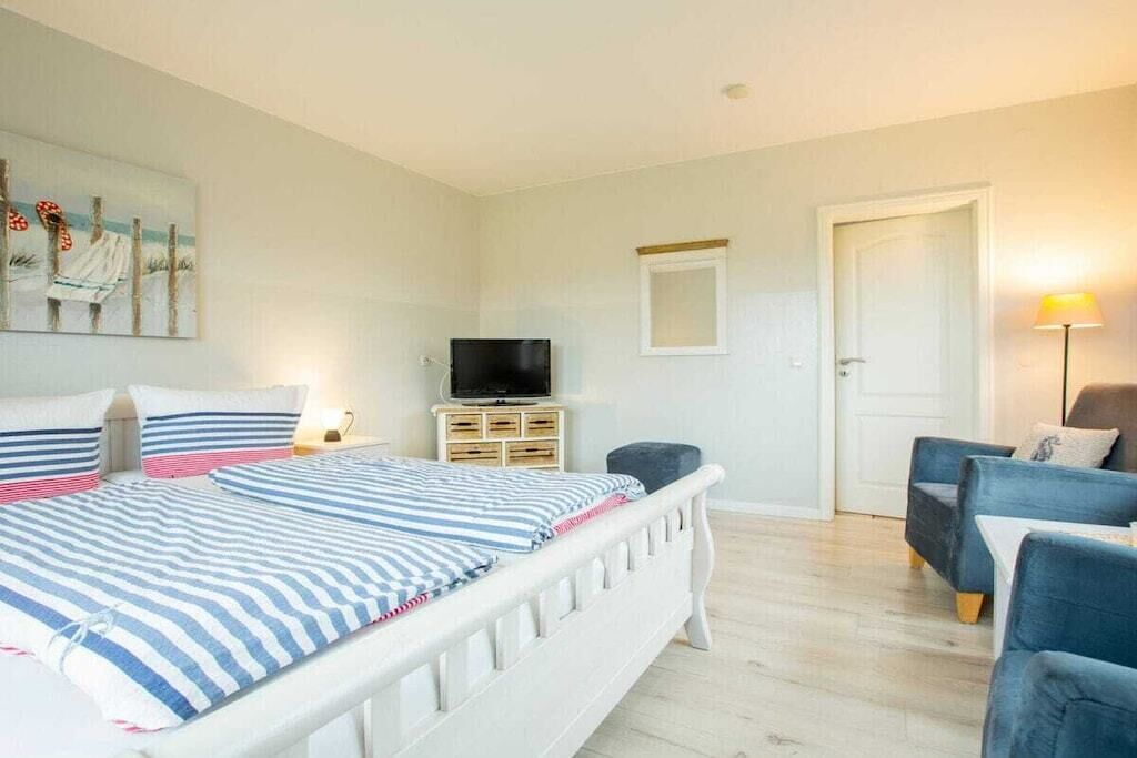 Ein Schlafzimmer mit einem Bett, einem Fernseher, einem Sessel und einer Lampe.