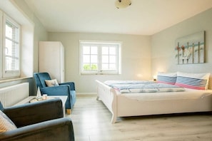 Ein Schlafzimmer mit Bett, Sessel, Heizkörper und Fenster.